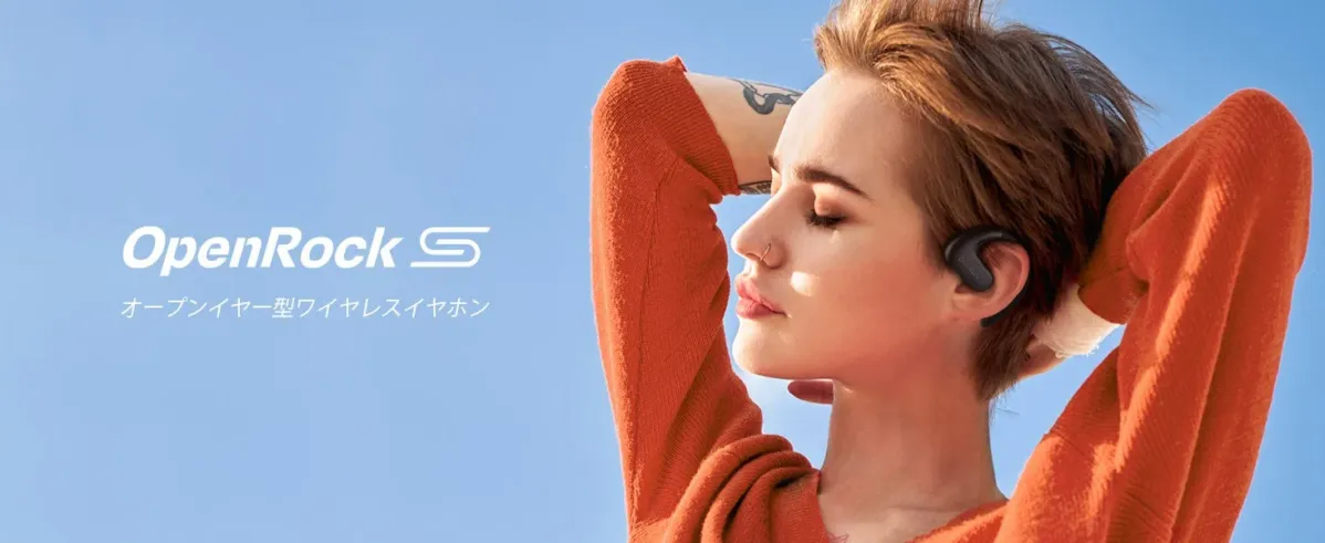 青空の下、オープンイヤー型ワイヤレスイヤホン「OpenRock S」を装着した女性の横顔が写っている広告画像です。