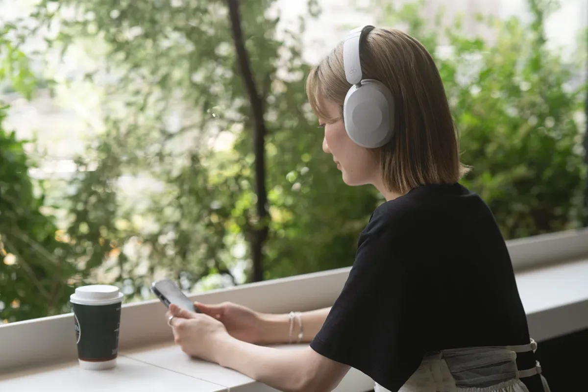 ヘッドホンを装着しコーヒーを飲みながら窓の外を眺める女性