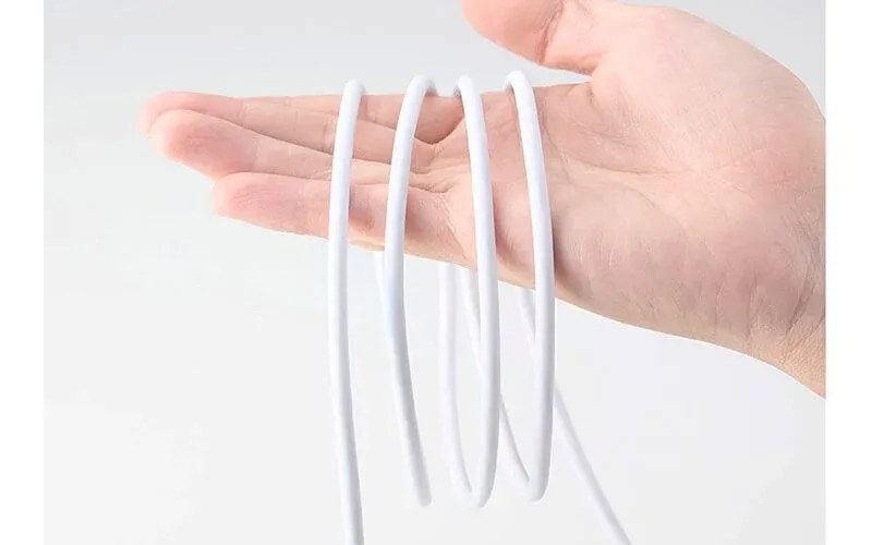 人の手が白い柔軟なケーブルを複数回巻きつけて持っている様子