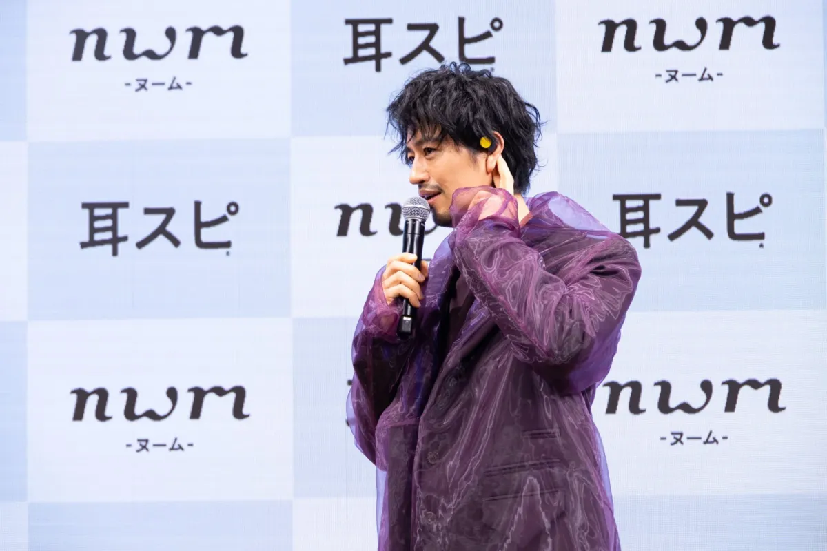 紫色のジャケットを着用しマイクを持って話す斎藤工さん