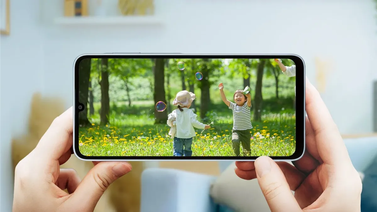 野原でシャボン玉をする子供たちを映すスマートフォン