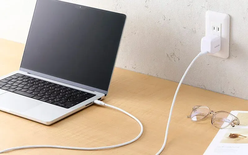 木製のデスクでノートパソコンが充電されている様子