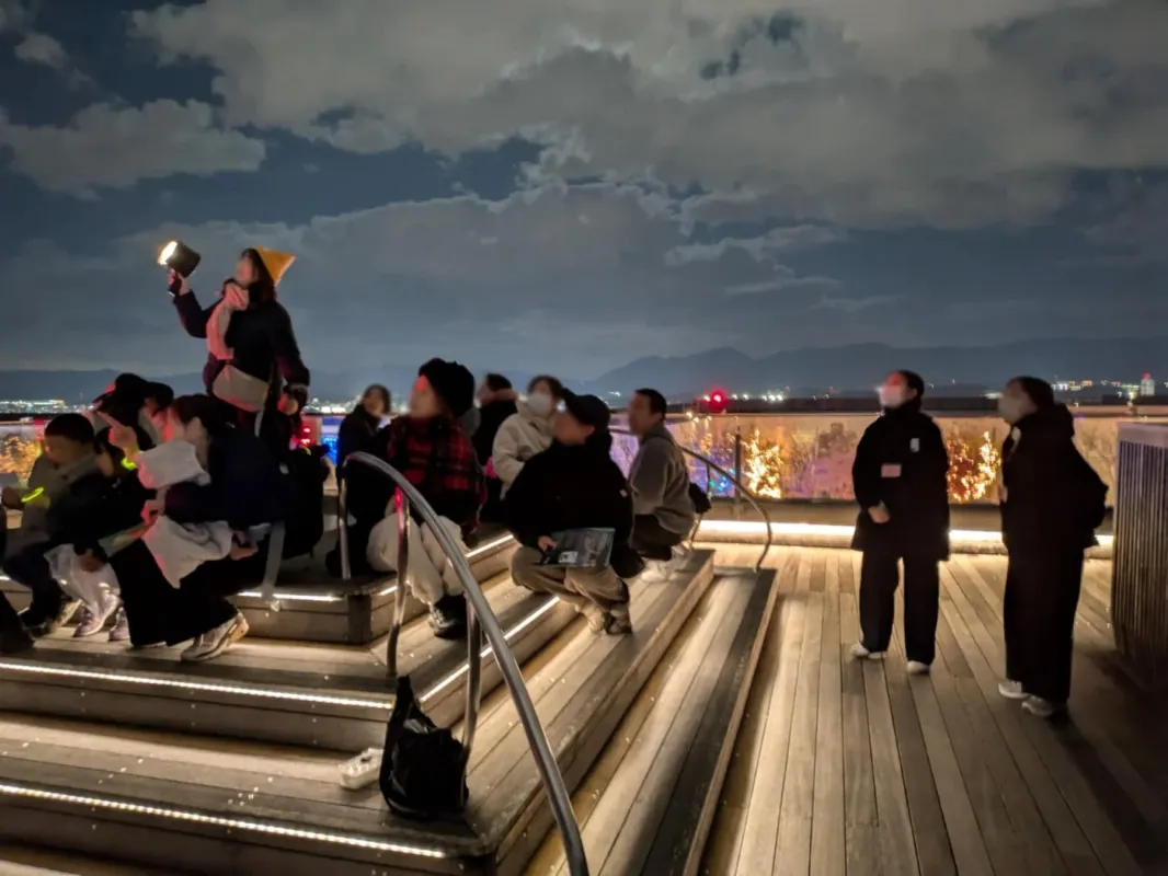 夜間の屋外で空を見上げる人々