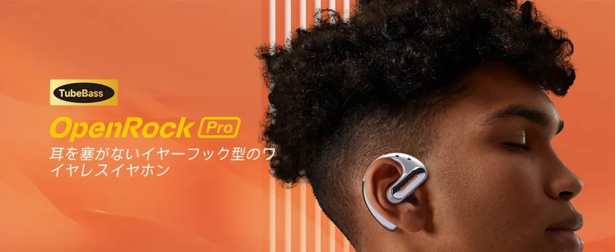 オレンジ色の背景をバックに、耳を塞がないイヤーフック型ワイヤレスイヤホン「TubeBass OpenRock Pro」を装着した男性の横顔が写っています。
