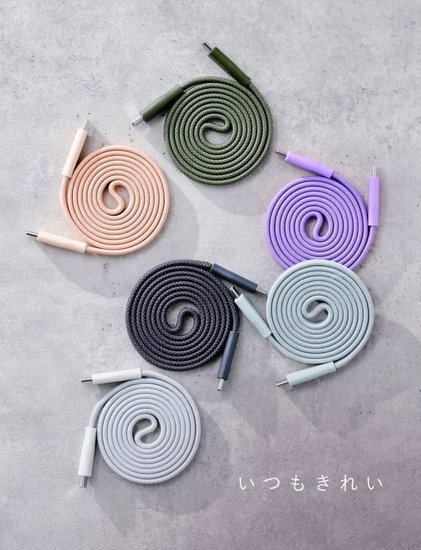 様々な色の充電ケーブルが、それぞれ丁寧に巻かれてコンクリート調の背景に美しく配置されています