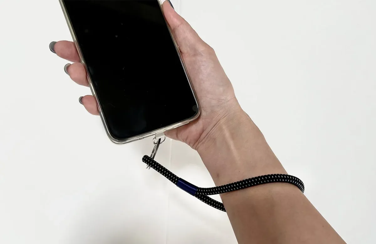 スマートフォンにリストストラップを取り付け、手首に通している様子