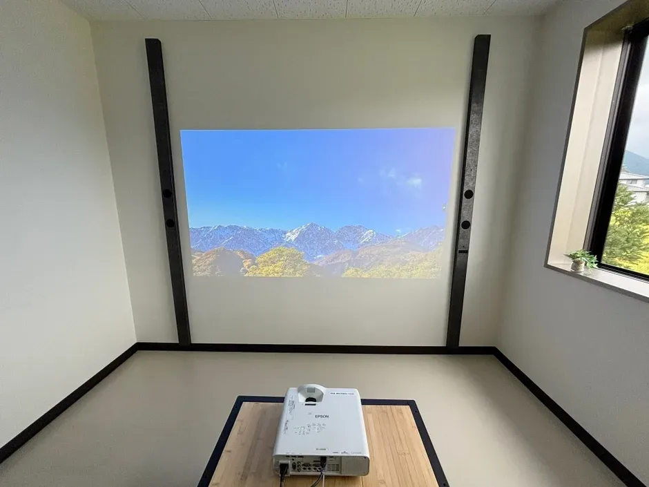 プロジェクターが設置された部屋で、壁には美しい山岳風景が投影されています