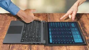 木製のテーブルに置かれた革新的なデュアルスクリーンデバイスを、2人の人物が指差して操作しています。