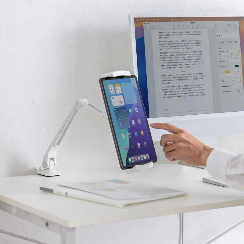 デスク上でモニターとアームスタンドに固定されたiPadが並び、ユーザーがiPadを操作しているワークスペースの風景。PCとタブレットを併用し、効率的に作業を進めるデジタル環境を表現している。
