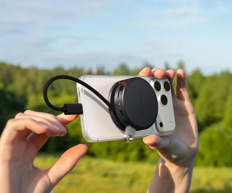 屋外で、ユーザーがSatechi製の多機能ハブを接続したiPhoneを持っている様子