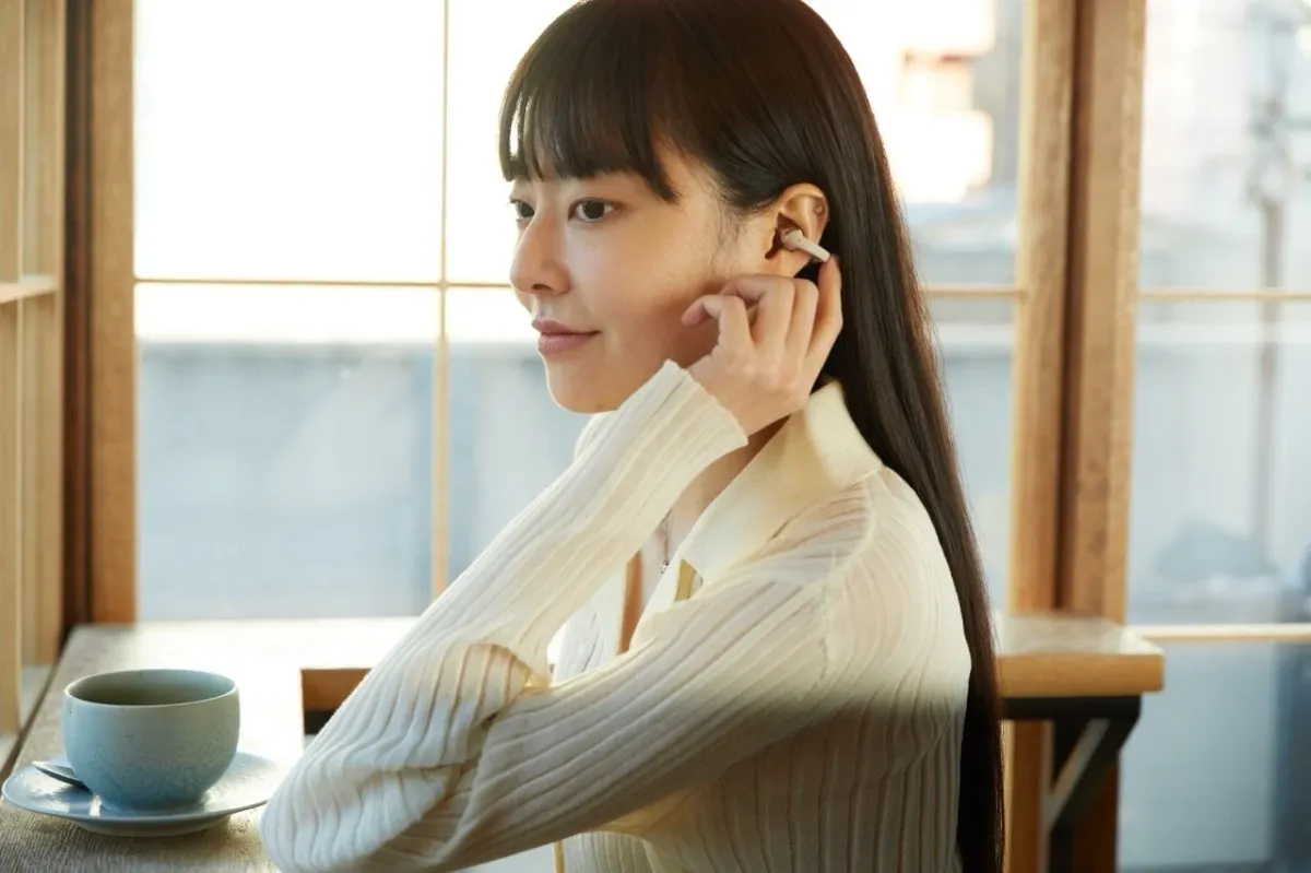 イヤホンを装着してカフェでリラックスする女性