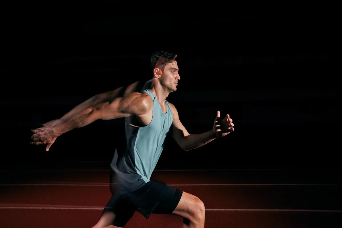 トラックを走る男性ランナーとShokzイヤホン