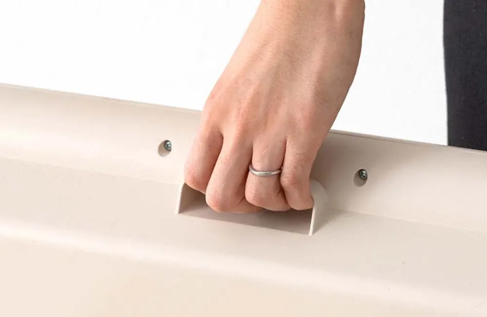 リングをはめた手が、ベージュ色の物体に取り付けられた持ち手をしっかりと掴んでいる様子です。家具や収納ボックスを動かしたり、開けたりする場面を想像させます。