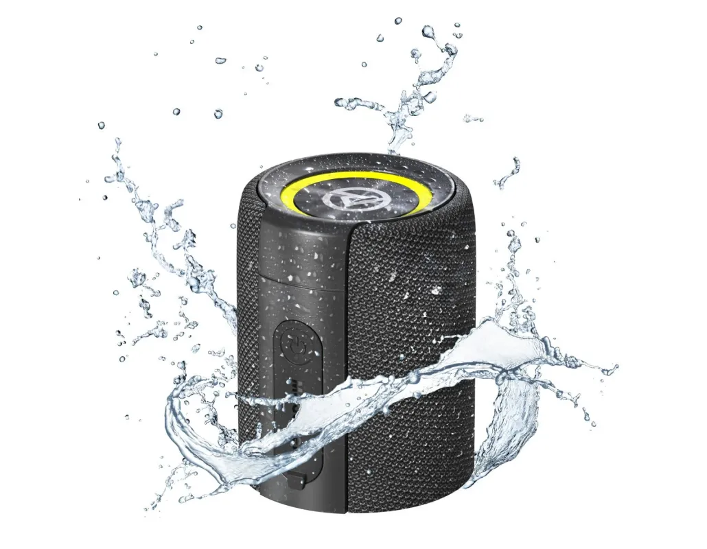 白い背景に、水しぶきを浴びる黒色のポータブルスピーカーが写っています。このスピーカーは防水性能を持つことを示唆しており、上部には黄色のアクセントとロゴマークが見られます。