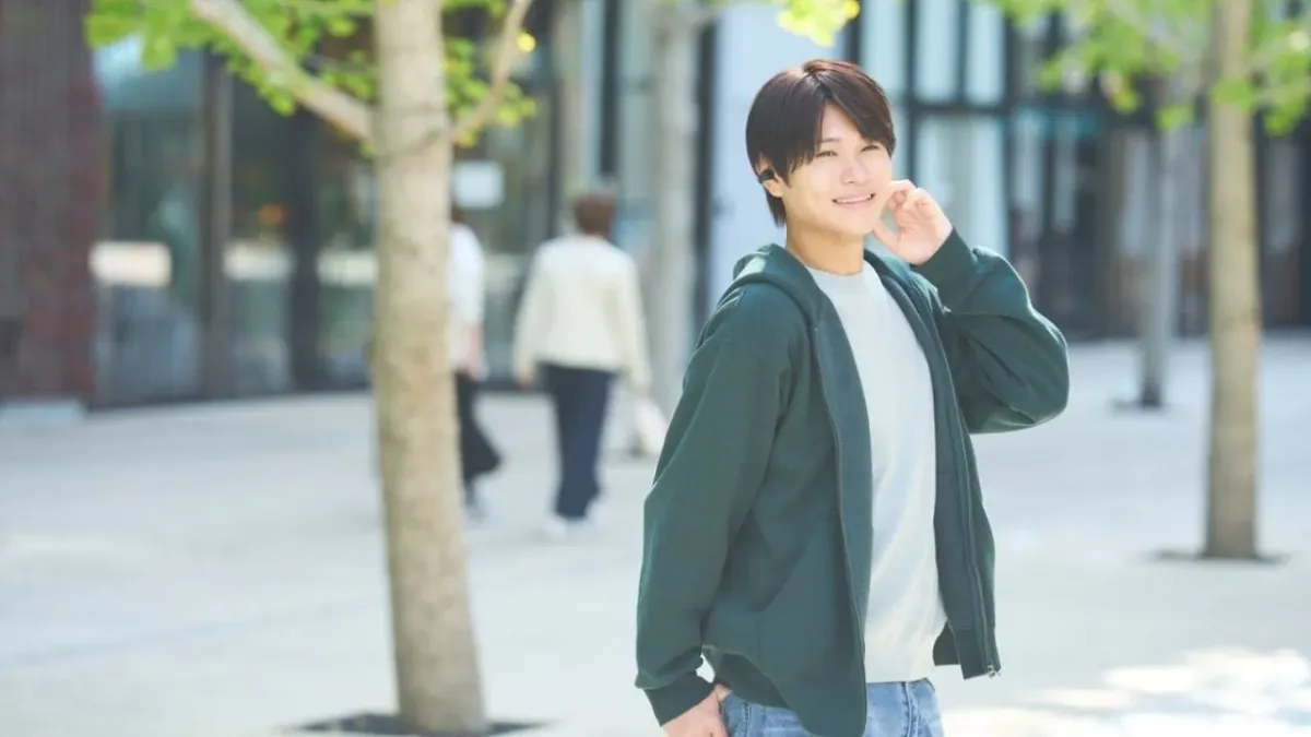 イヤホンを装着し、屋外で笑顔を見せる男性