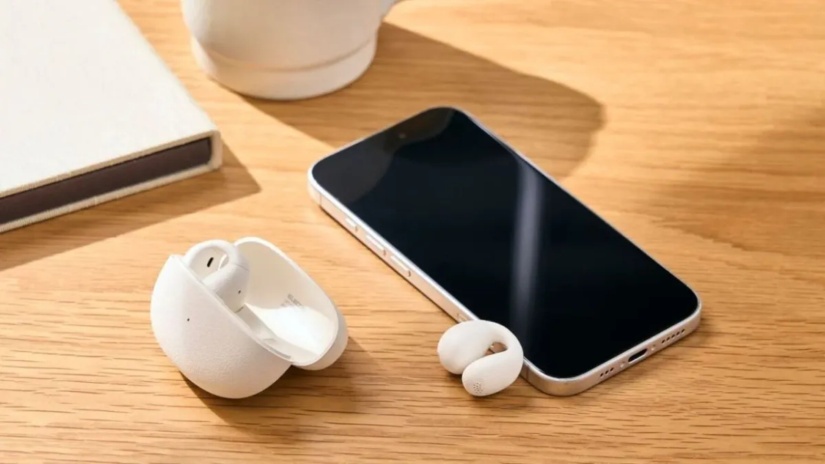 スマートフォン、イヤホン、充電ケースが木目のデスクに置かれている様子