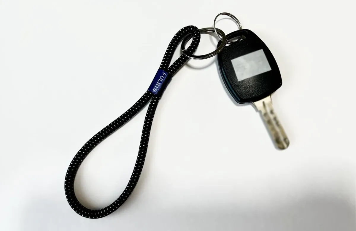 白い背景に置かれた、黒いストラップ付きの車の鍵