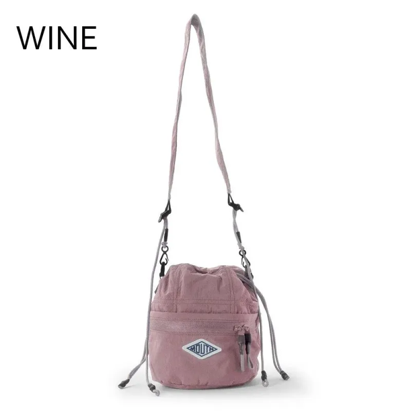 白い背景に吊るされたピンク色の巾着型ショルダーバッグ