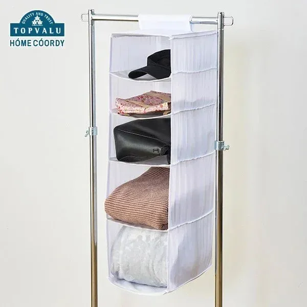 白い5段の吊り下げ式収納ラックが、ポールハンガーに掛けられています。帽子、衣類、バッグなどがきれいに整理されて収納されており、クローゼット内のスペースを有効活用できるアイテムです。