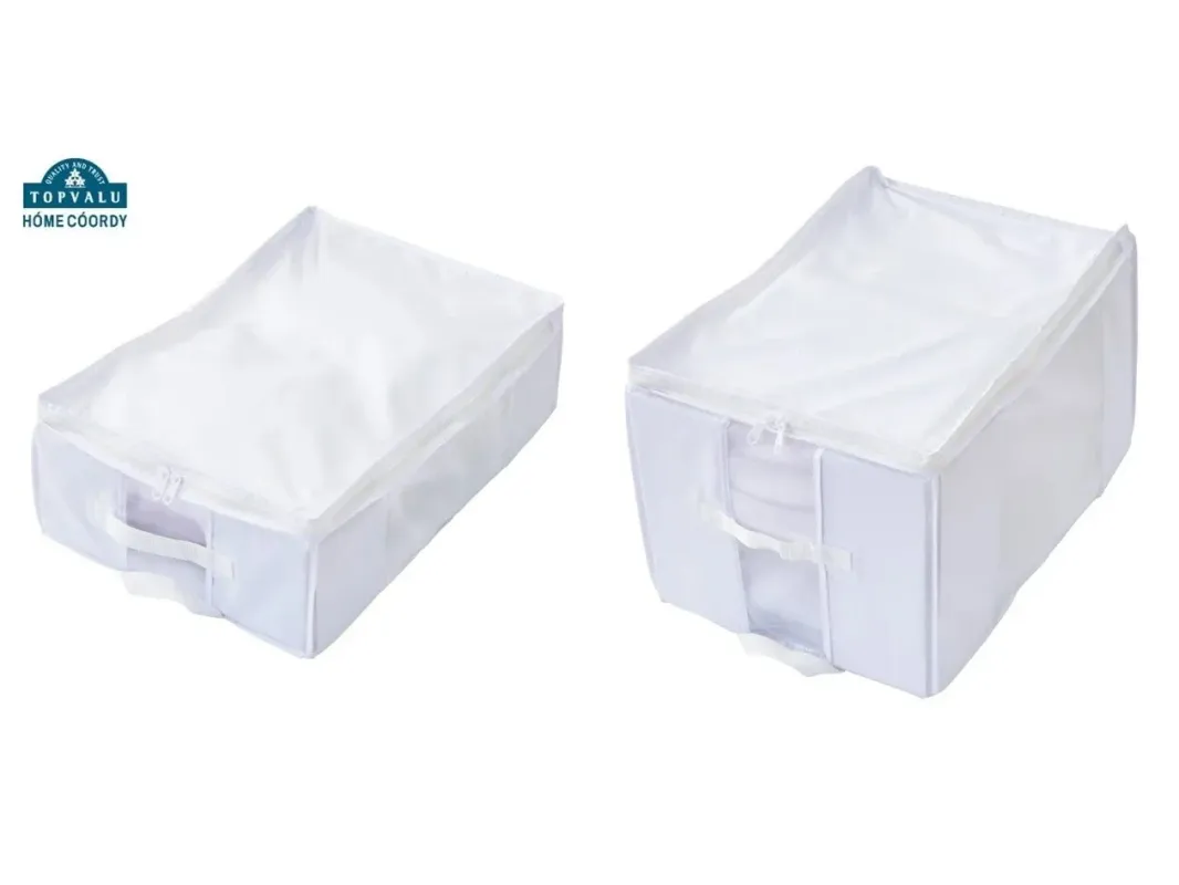 白くてシンプルな布製の収納ケースが2つ、異なる角度から写されています。ファスナーと取っ手が付いており、衣類や寝具の整理に便利です。