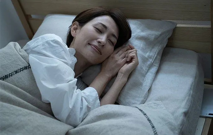 ベッドで安らかな寝顔を見せて眠る女性の姿