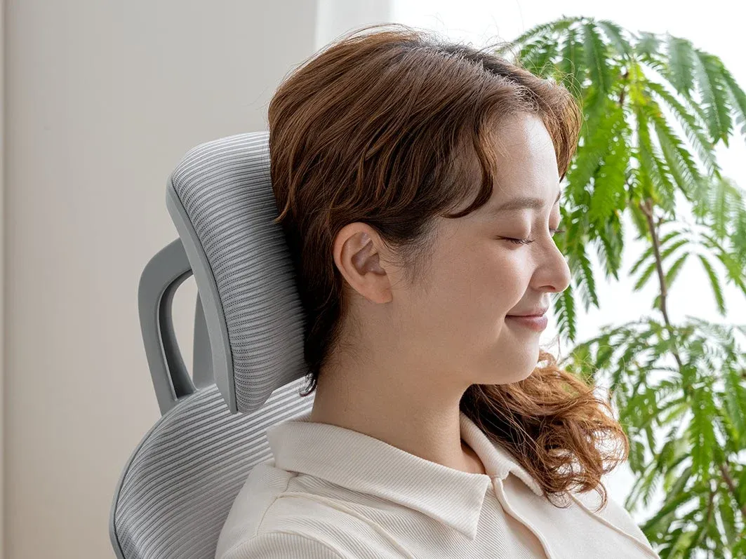オフィスチェアのヘッドレストに頭をもたせかける女性