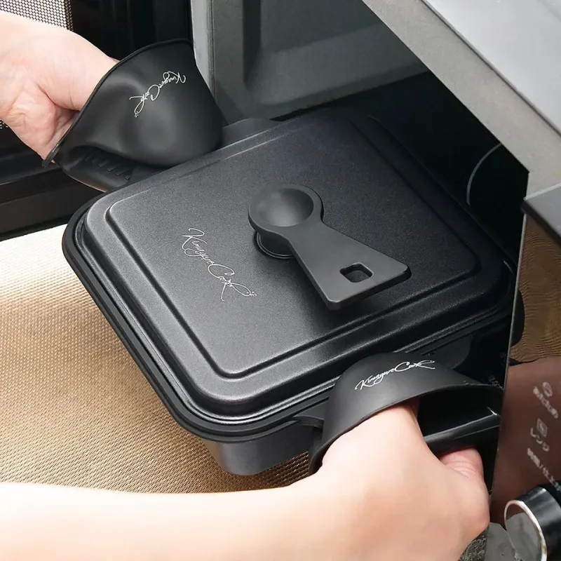 耐熱ミトンを使い、電子レンジに黒い四角い調理器具を出し入れしている様子