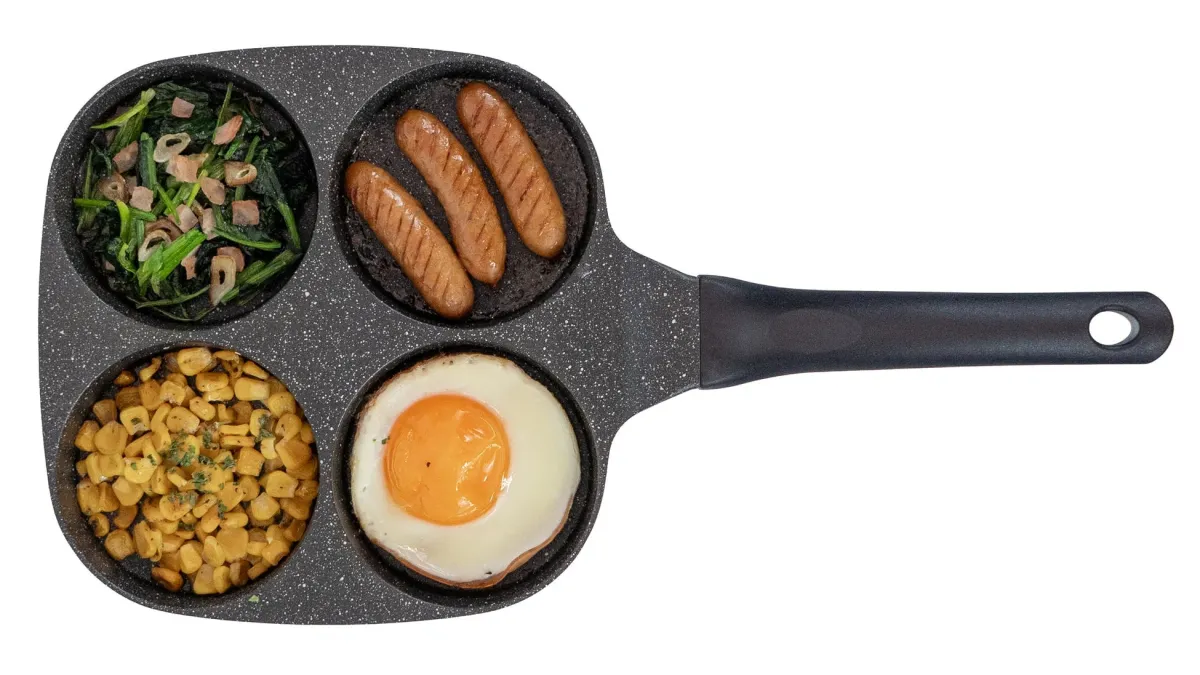 仕切り付きフライパンで調理された朝食の俯瞰画像です。目玉焼き、ソーセージ、ほうれん草のソテー、コーンがそれぞれの区画に盛り付けられ、手軽に準備できる食卓の様子を示しています。