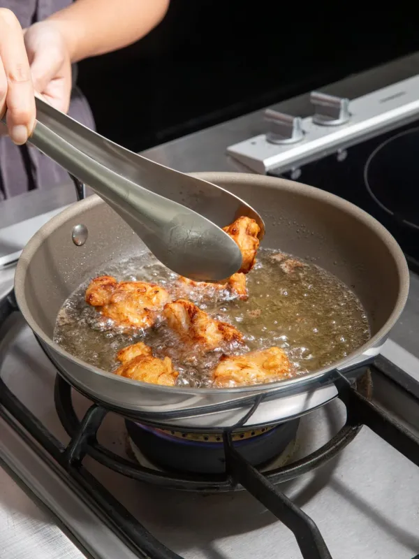 トングで揚げ物を調理する様子