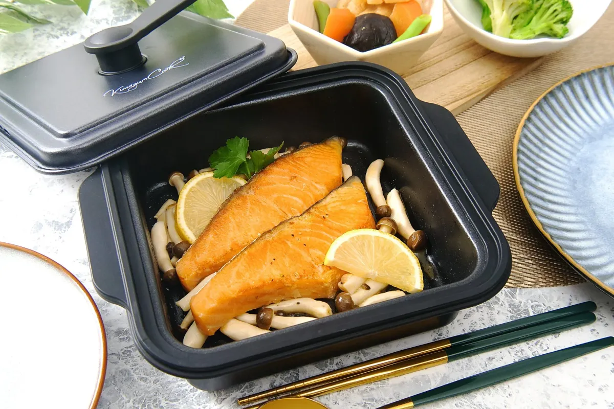 黒い調理ポットに入った焼き鮭とキノコの料理