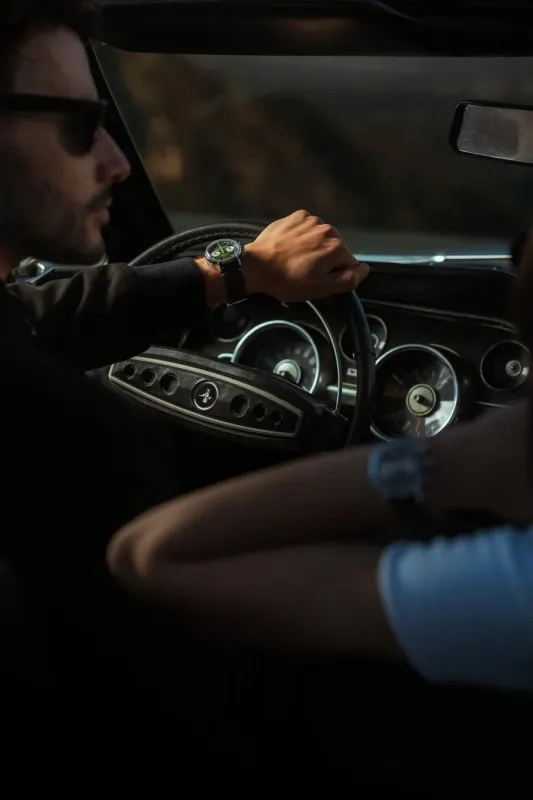 クラシックカーを運転する男性と腕時計