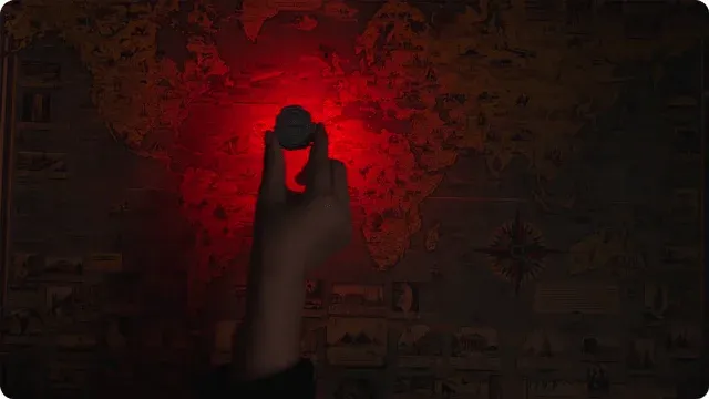 暗闇の中、手が世界地図の上に何か丸い物体を掲げており、その下から不気味な赤い光が放たれています