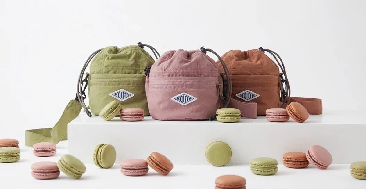 淡いグリーン、ピンク、ブラウンの3色の巾着型ショルダーバッグとマカロン