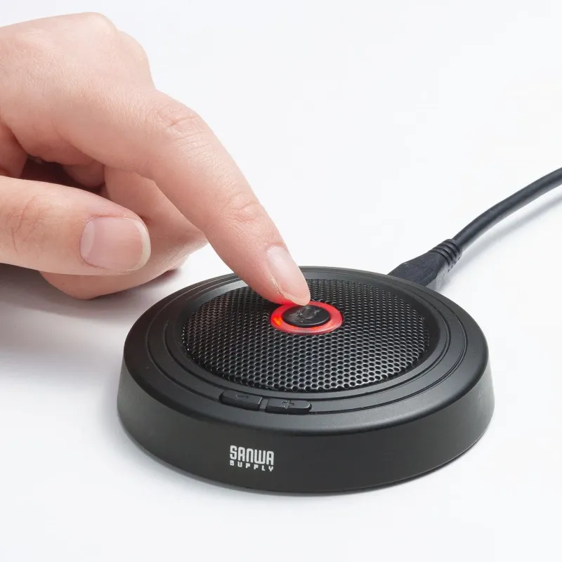 黒いデスクトップマイクのミュートボタンを指が押している様子