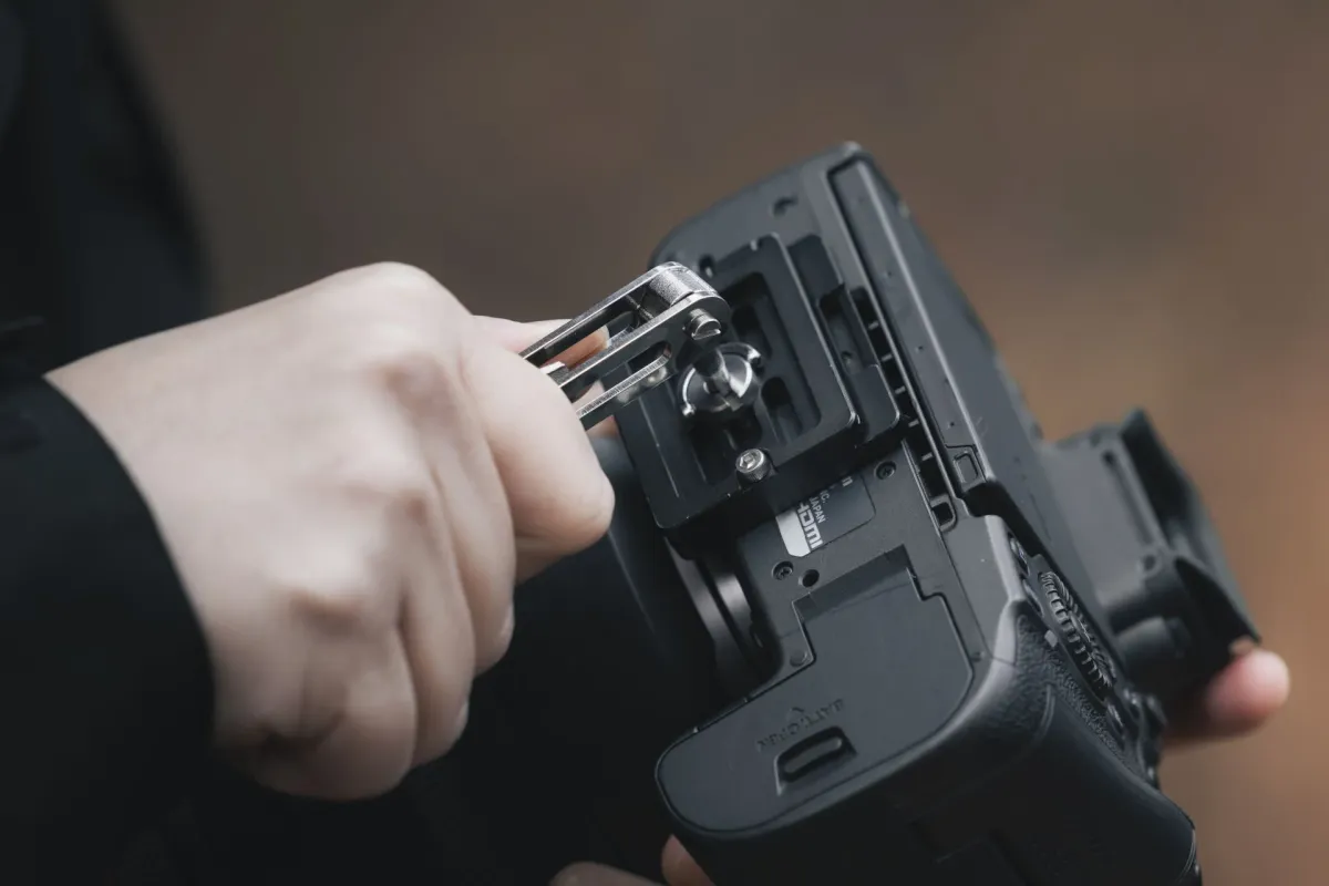 カメラのクイックリリースプレートを工具で調整する手元