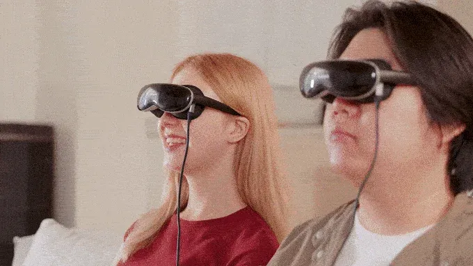 VR/ARヘッドセットを装着した男女が、笑顔で同じ仮想体験を楽しんでいる様子を捉えた画像です。室内で最新のテクノロジーを活用したエンターテイメントに没頭しています。