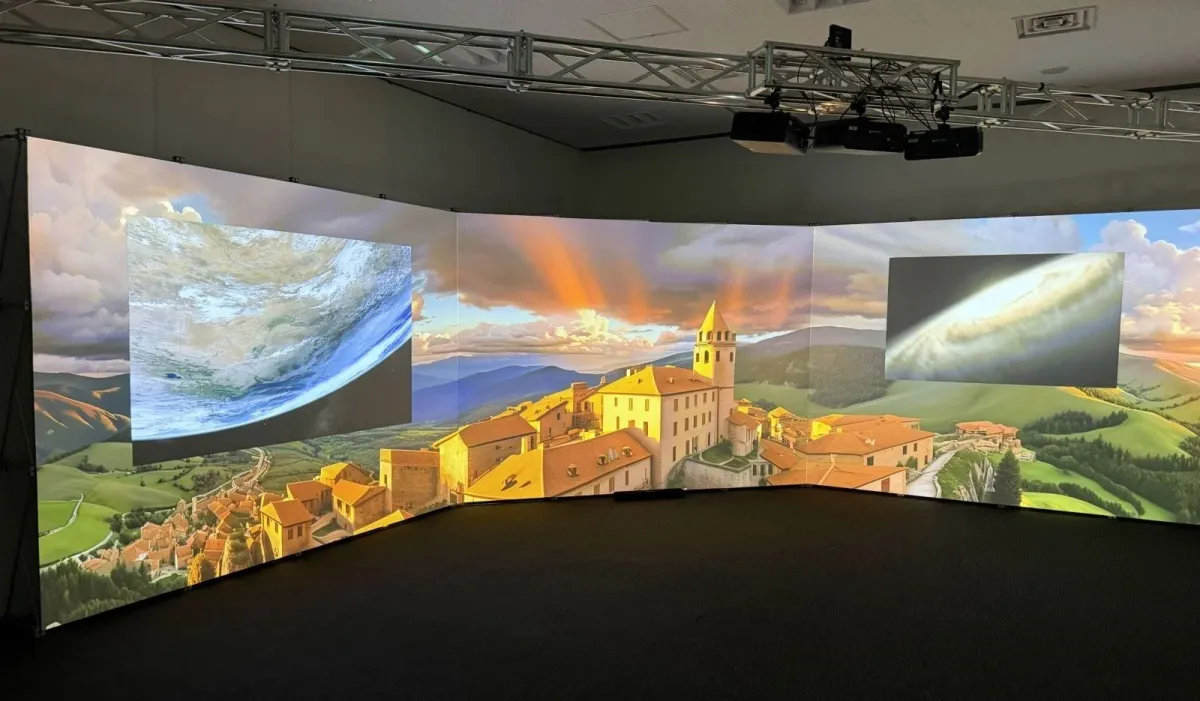 湾曲した大型スクリーンに夕焼けの空と街並み、地球、銀河の映像が投影された没入型ディスプレイ