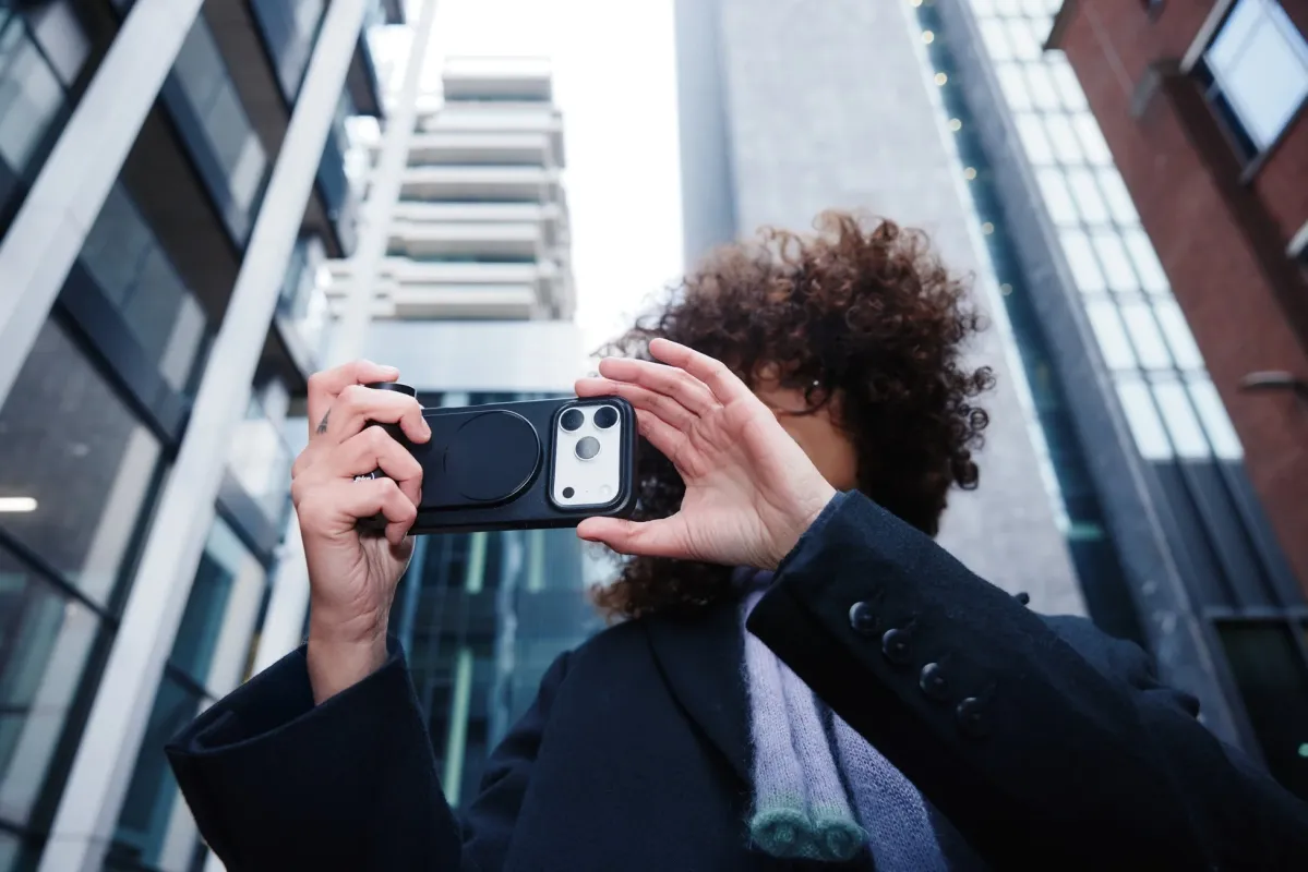 iPhoneにレンズアタッチメントを装着して撮影する人物
