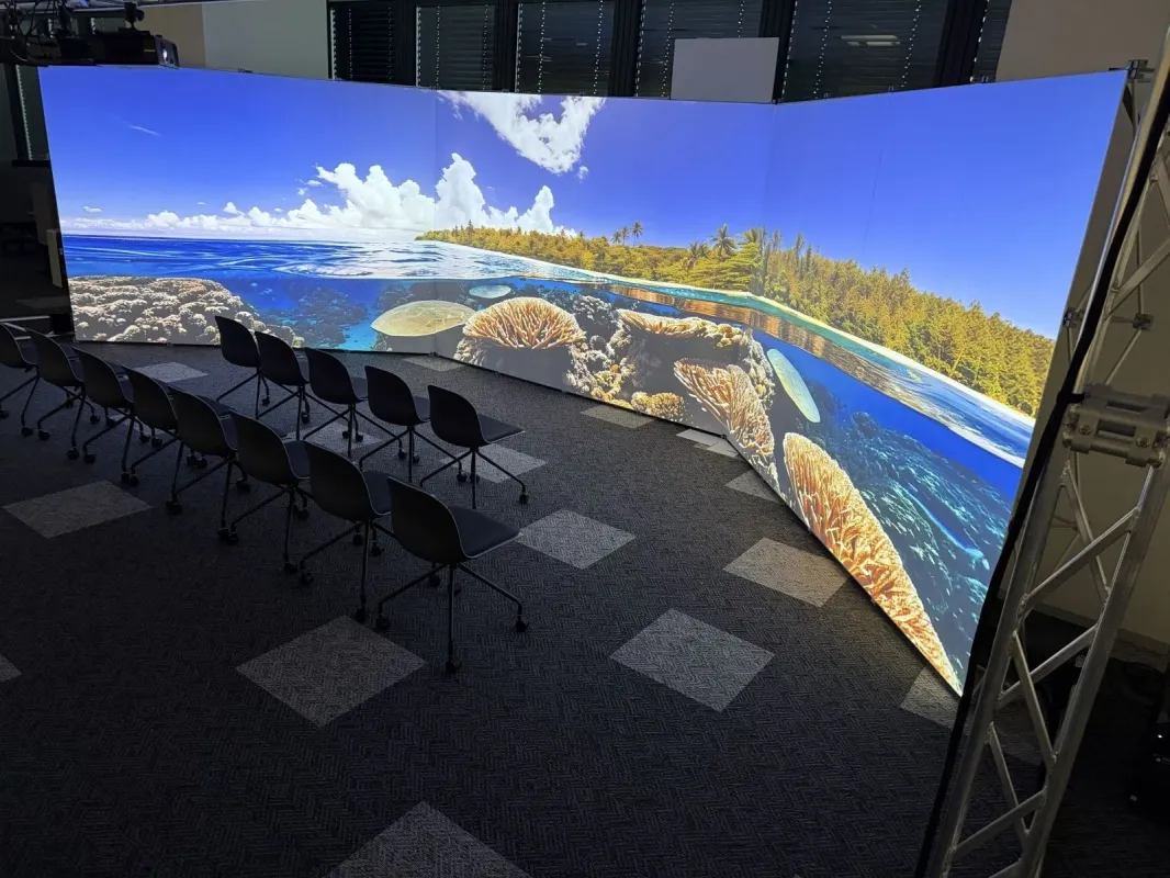 湾曲した大型スクリーンに熱帯の海が投影された会議室のような空間