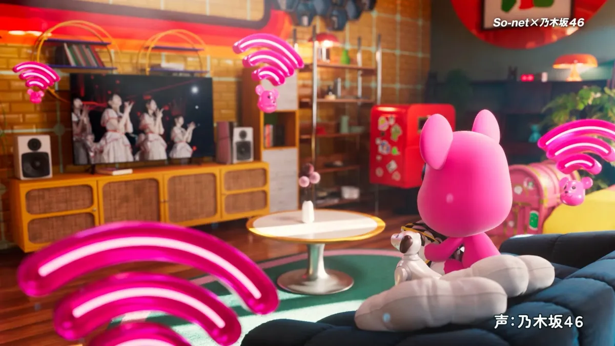 ピンクのキャラクターがリビングルームでテレビを見ている様子。画面には乃木坂46が映り、Wi-Fiのシンボルが飛び交う、カラフルでポップな雰囲気の画像です。