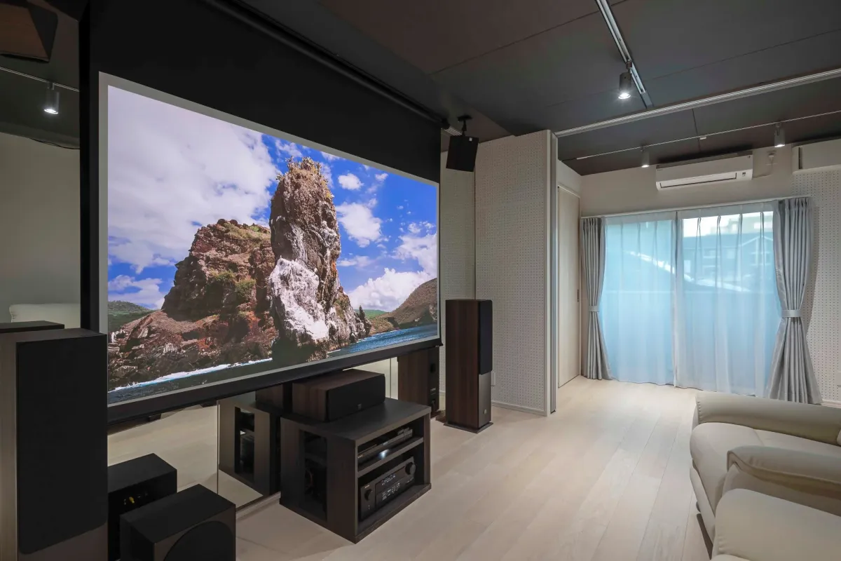 モダンなリビングルームに設置された、大画面プロジェクターと複数のスピーカーを備えたホームシアターシステム