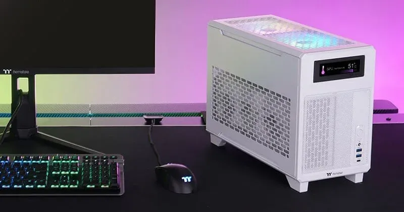 白いゲーミングPCケースを中心に、RGBライティングが施されたキーボードやモニターが並ぶPCデスクのセットアップ。PCケースのディスプレイにはGPU温度が表示されています。