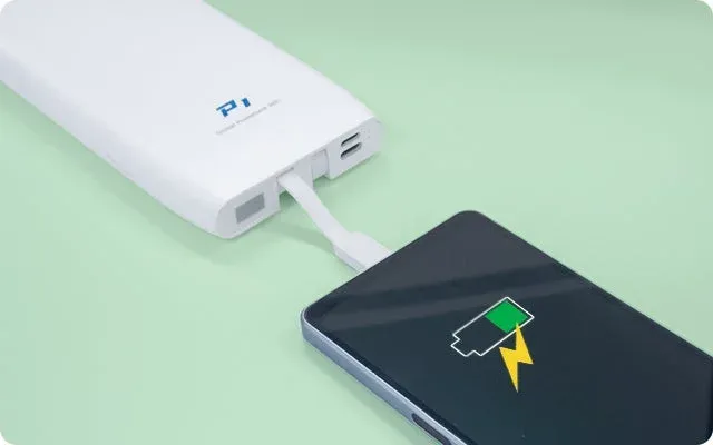 白いモバイルバッテリーが黒いスマートフォンに接続され充電している様子