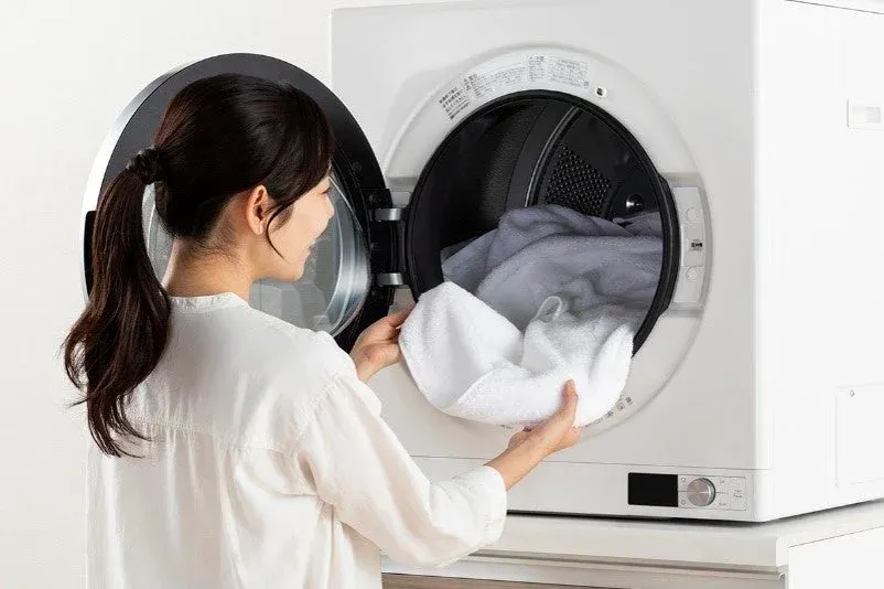 洗濯機に衣類を入れる女性