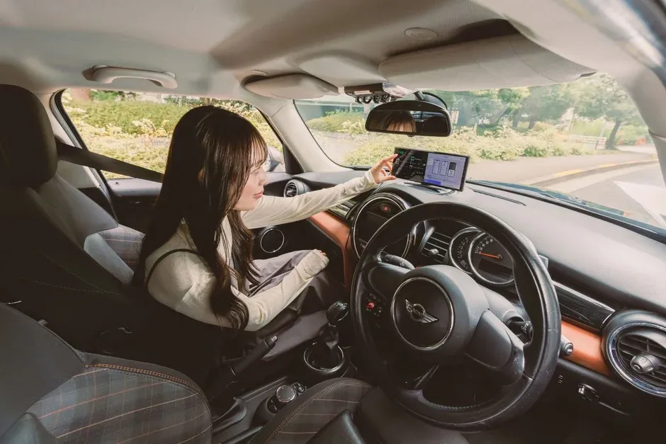 車の助手席に座る女性が、ダッシュボードに設置されたインフォテインメントシステムを操作している様子