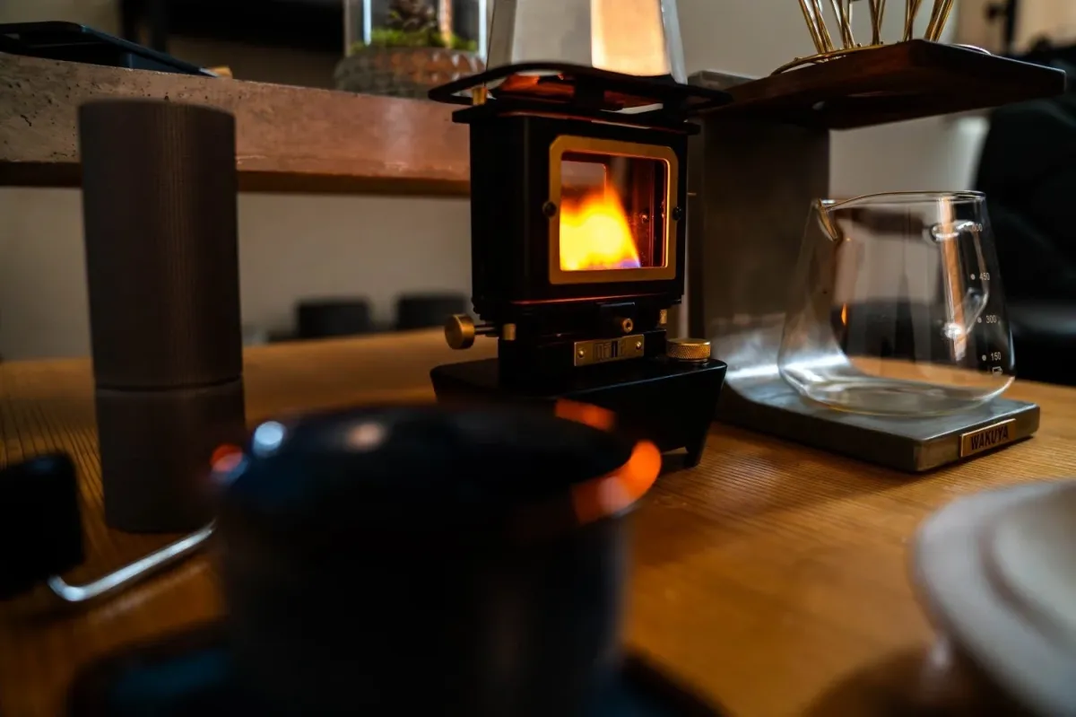 温かい炎が燃えるミニストーブを中心に、ハンドドリップコーヒーの準備が整えられた室内の様子
