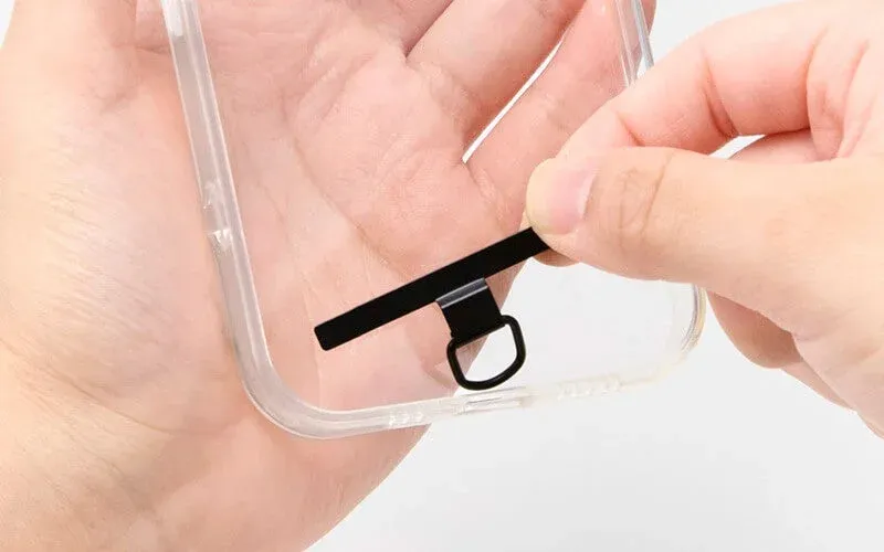 透明なスマホケースにストラップホルダーを装着する様子