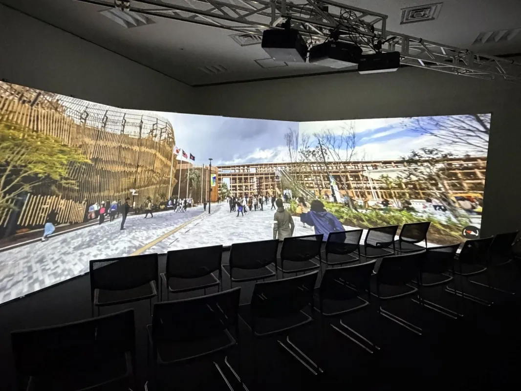 湾曲した大型スクリーンに近代的な建築物と人々が行き交う仮想空間が映し出された展示会会場