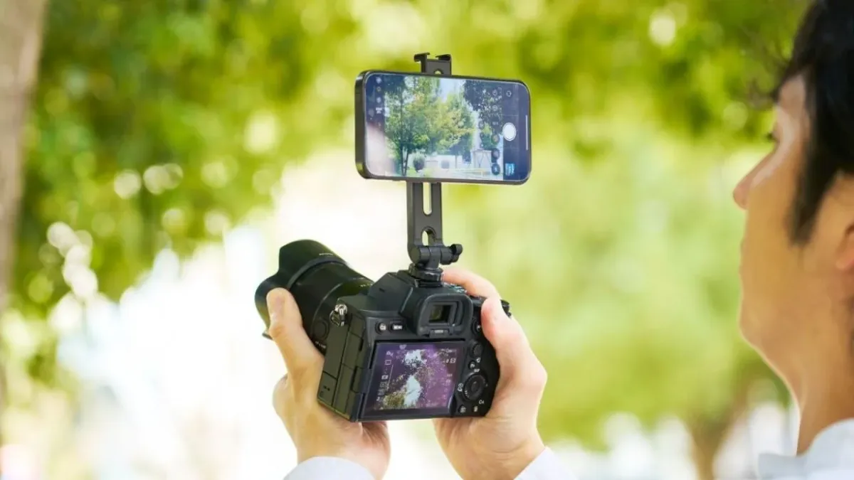 男性が一眼レフカメラにスマートフォンを装着して撮影しているシーン