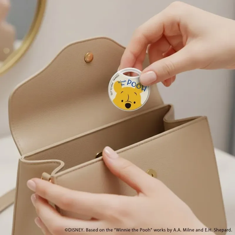 くまのプーさんのキーホルダーをハンドバッグに入れる様子